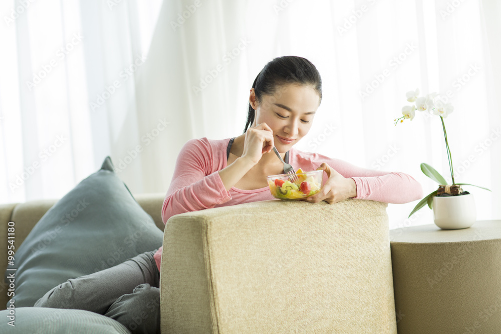 快乐的年轻女人吃水果沙拉