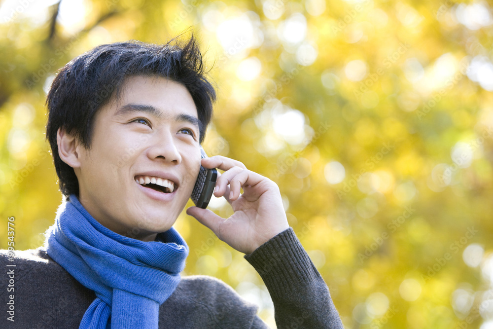 Young Man Talking on a Mobile Phone in a Park