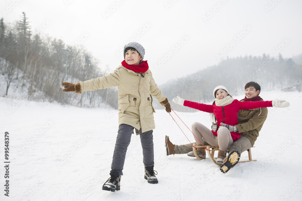 快乐的一家人在雪地上玩雪橇