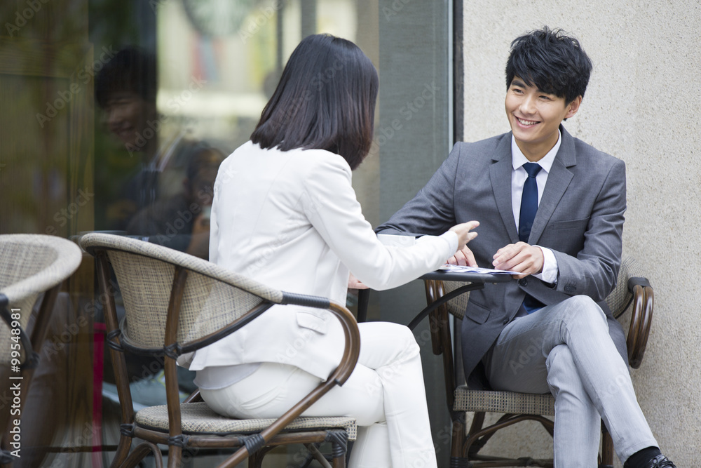 Two business person sitting at outdoor sidewalk café