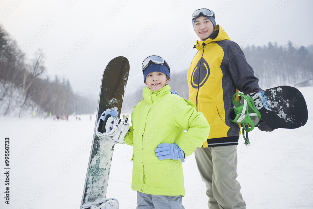 年轻的父子在雪地上玩滑雪板