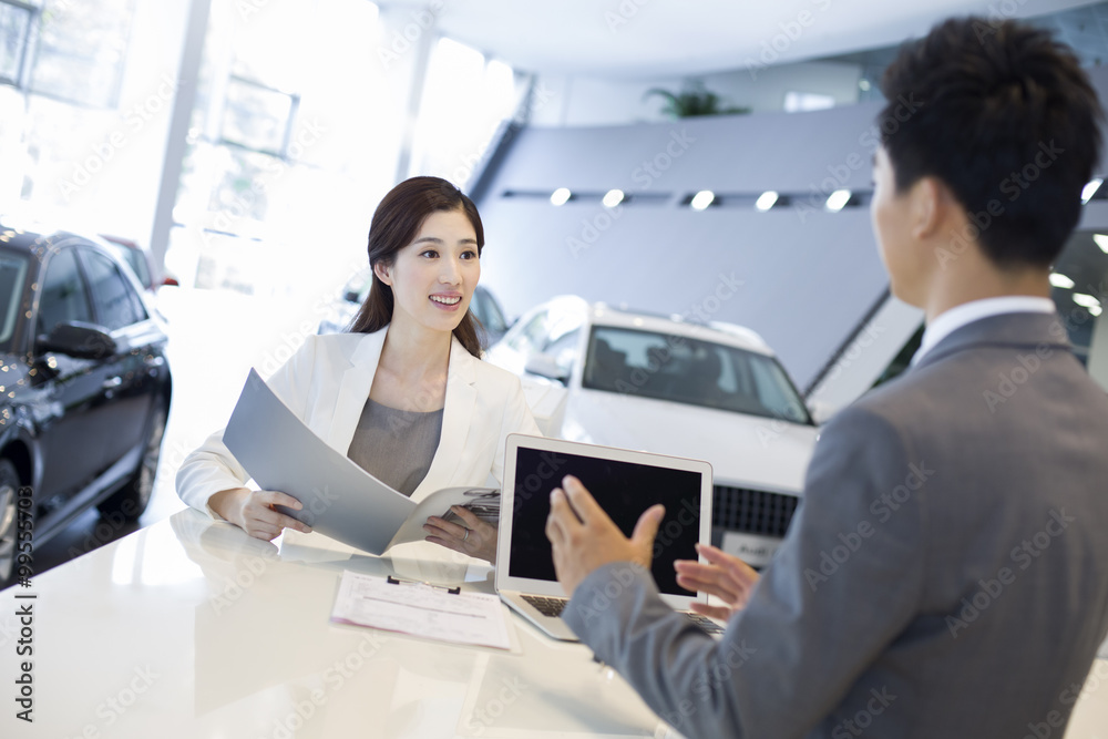 Young businesswoman buying car in showroom