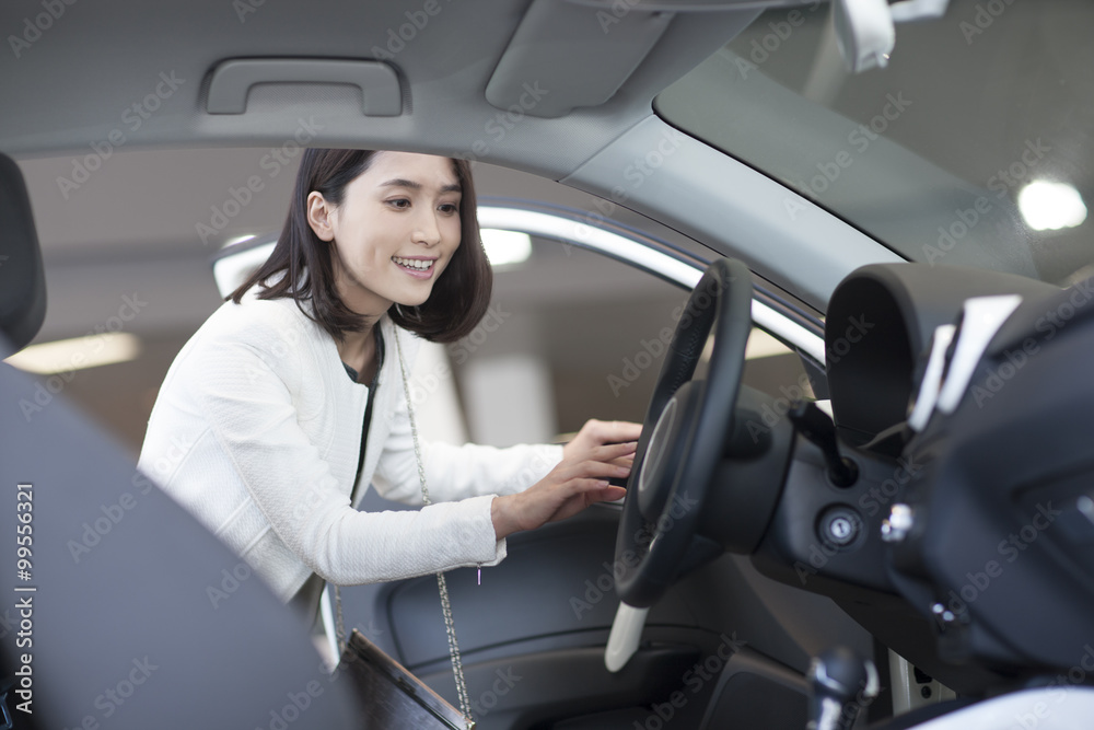 Young woman choosing car in showroom