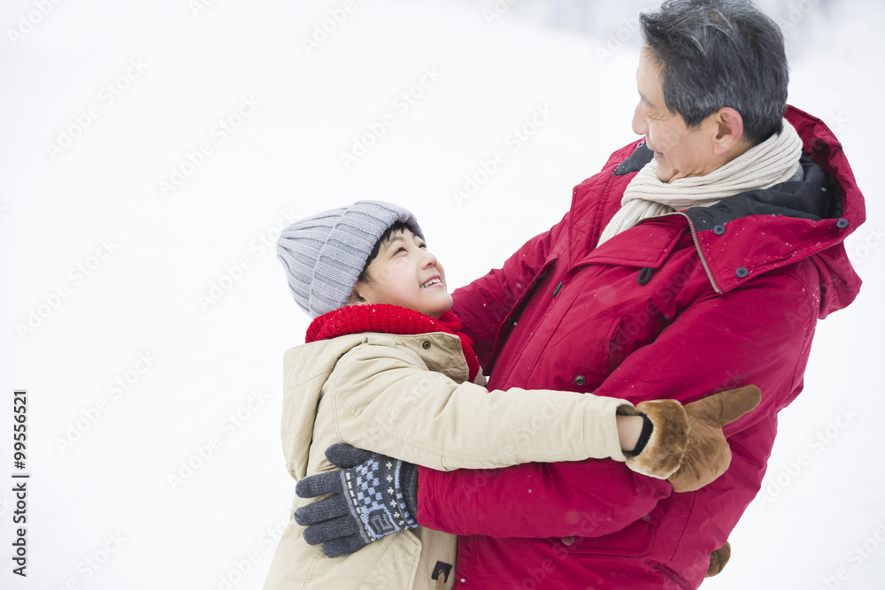 快乐的爷爷和孙子在雪地上拥抱