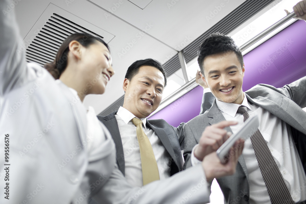 Cheerful business colleagues with smart phone in subway train