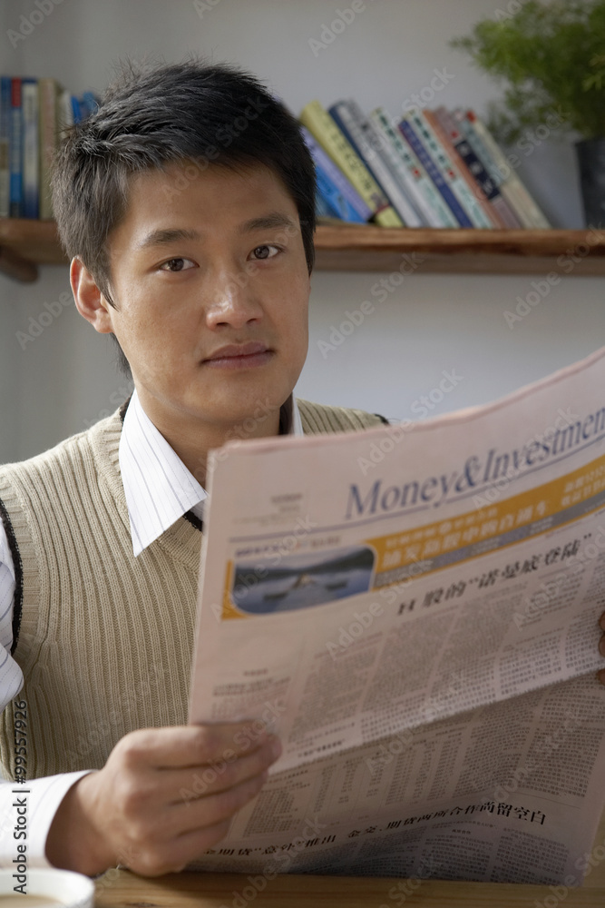 Man Sitting At Table, Reading A Newspaper