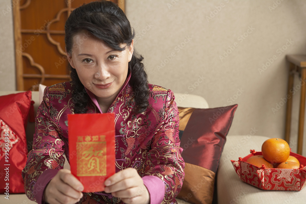 Woman Sitting On Couch Holding Out Red Chinese Paper