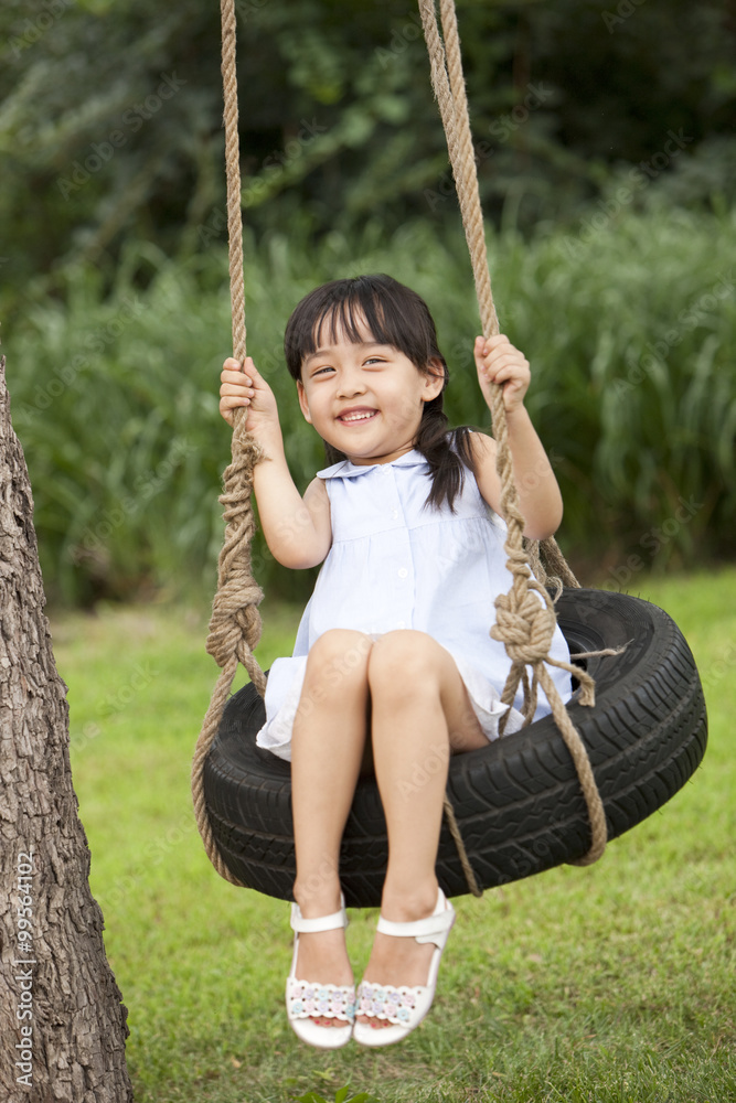 Excited little girl playing on a swing 