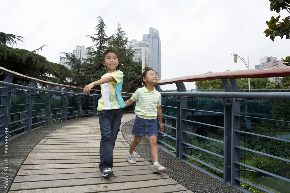 年轻男孩和年轻女孩在公园里跑过桥