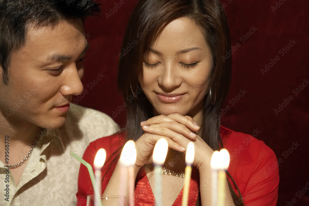 Couple Looking Happy Next To Lit Birthday Cake