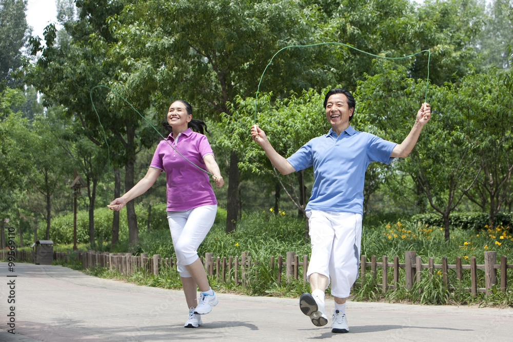 Senior couple playing jumping rope in park