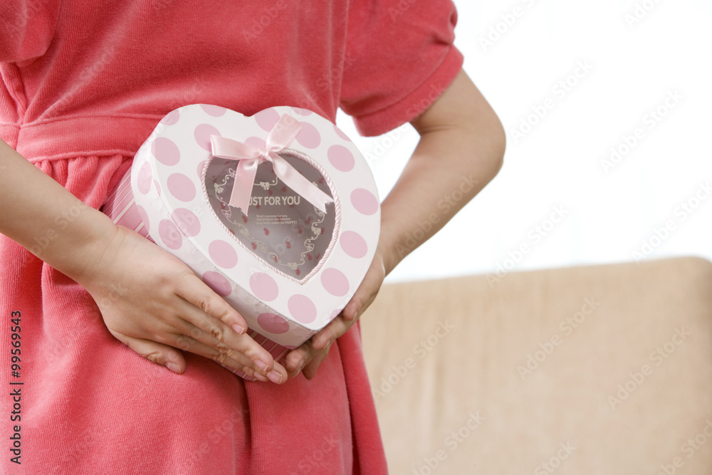 Girl holds heart-shaped box behind her back