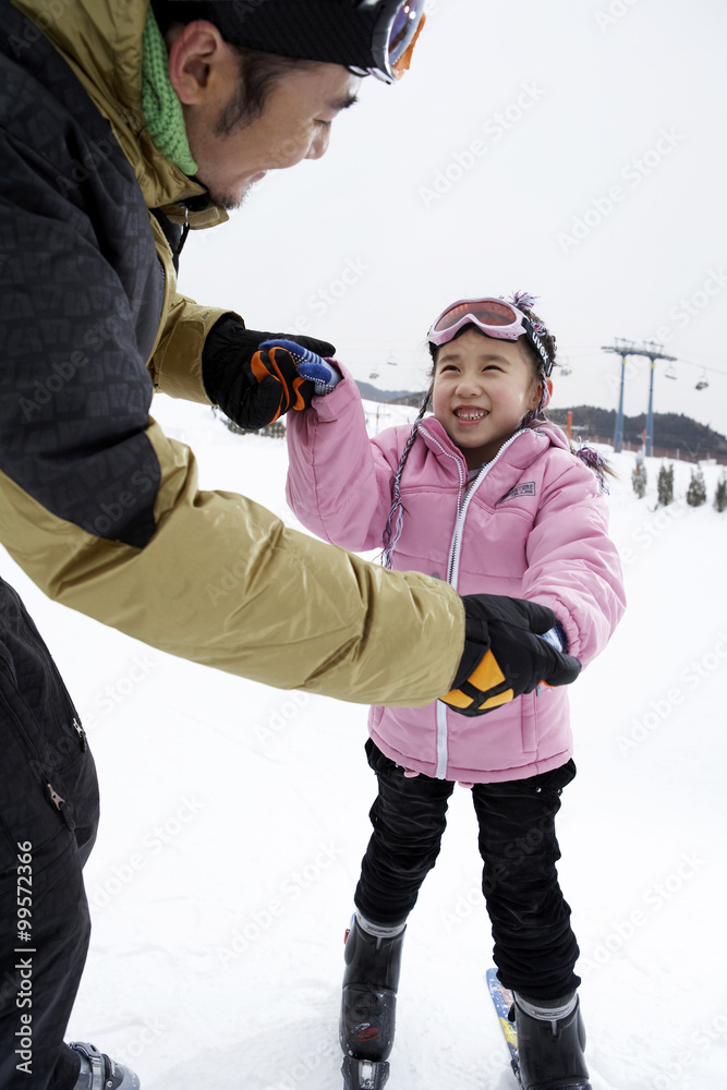 父亲帮助女儿滑雪