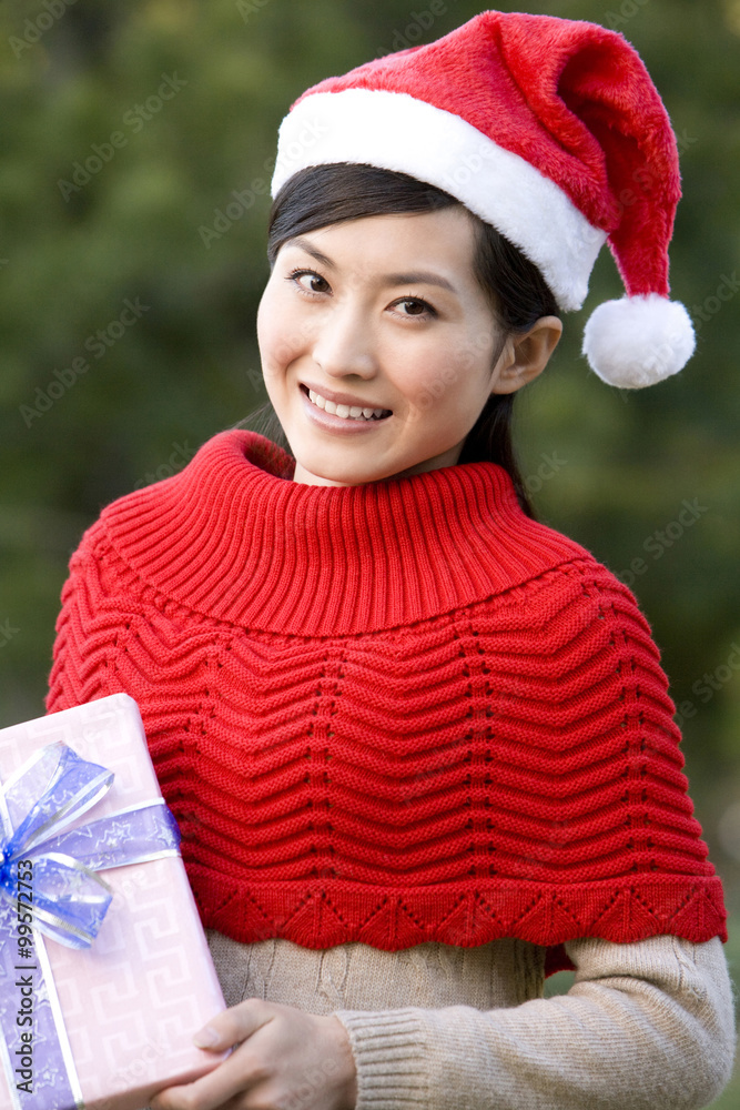 Young Woman in Santa Hat Holding Christmas Gift