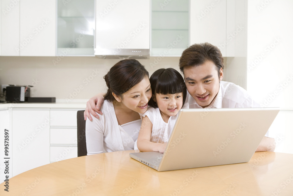 Little girl using laptop with her parents