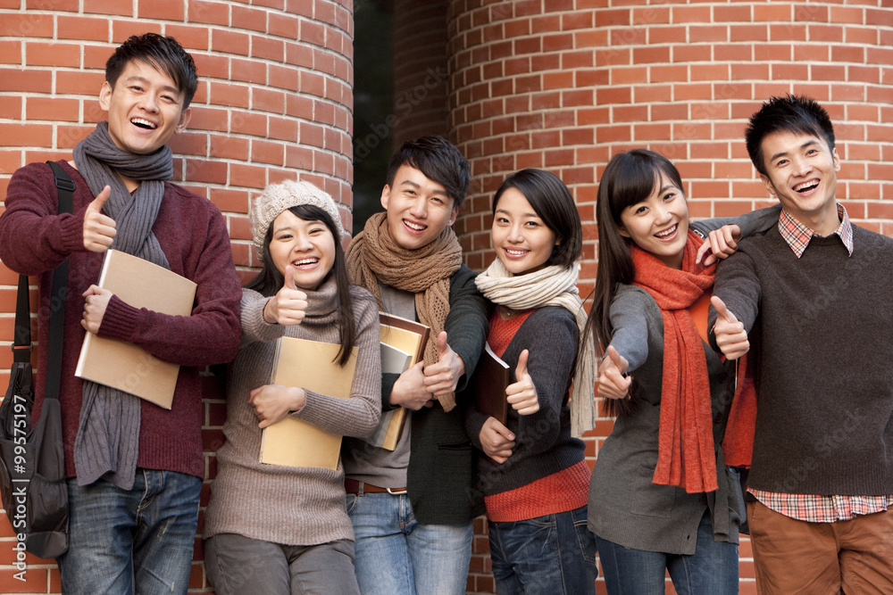 College students doing thumbs up in front of a university building