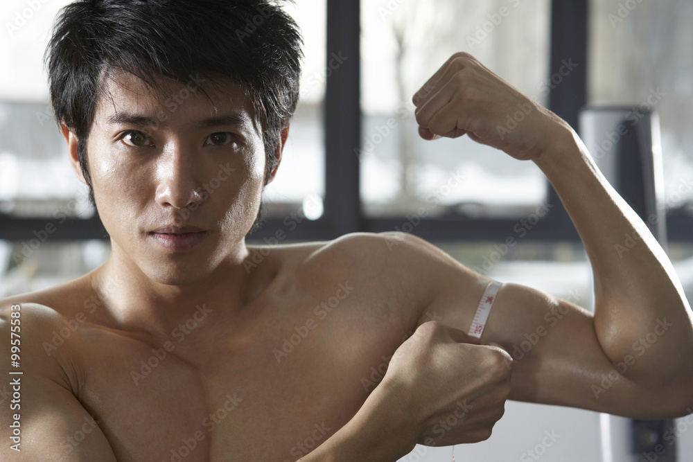 Young Man Measuring Muscles At The Gym