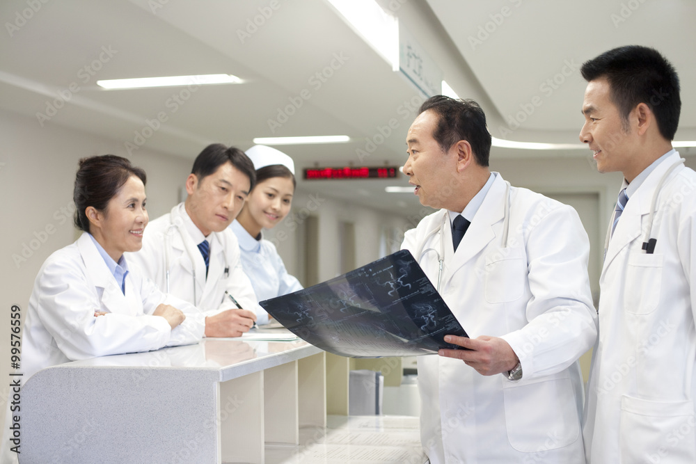 An older doctor showing a X-ray image to fellow doctors