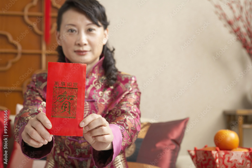 Woman Sitting On Couch Holding Out Red Chinese Paper