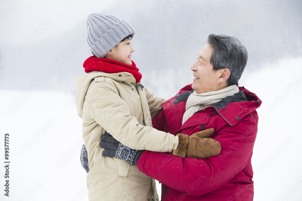 快乐的爷爷和孙子在雪地上拥抱