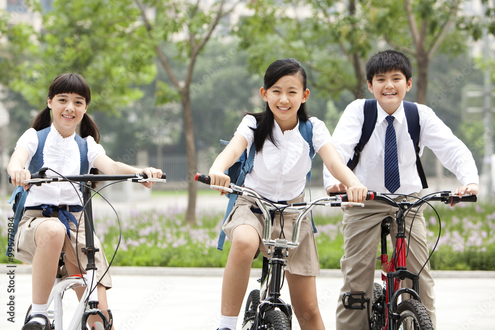 穿着制服、在户外骑自行车的快乐小学生