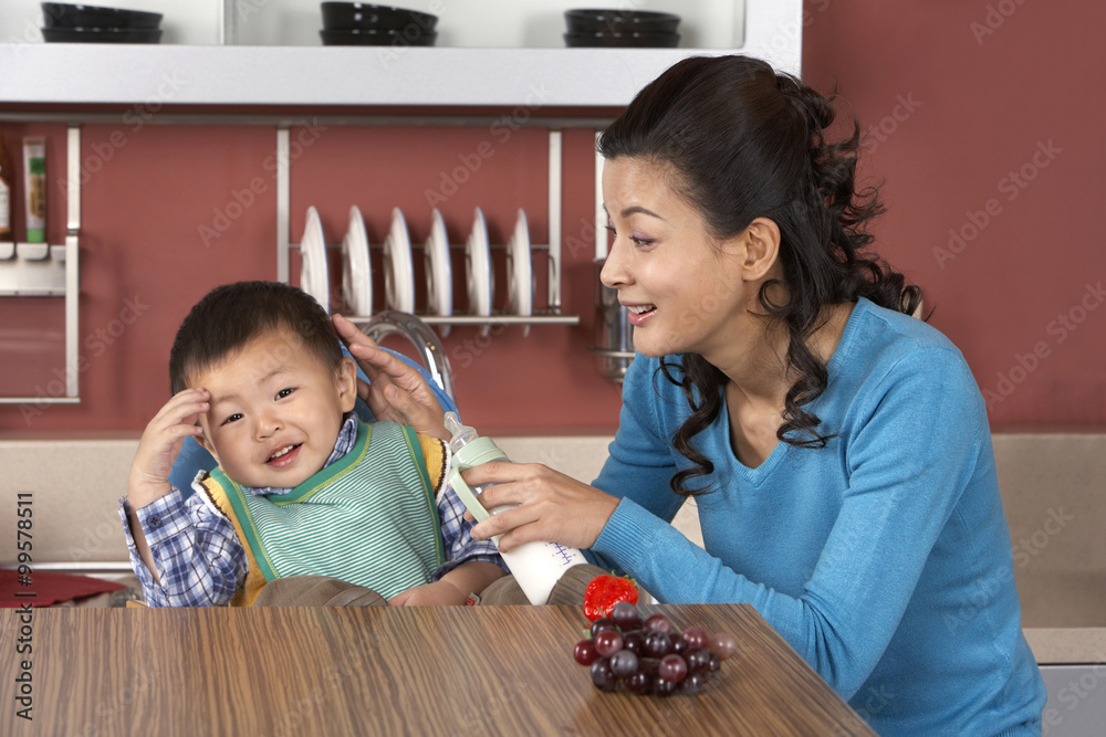 Woman trying to give her son a bottle of milk