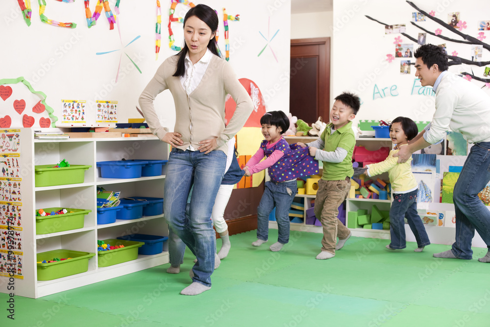 Happy kindergarten children and teachers playing games