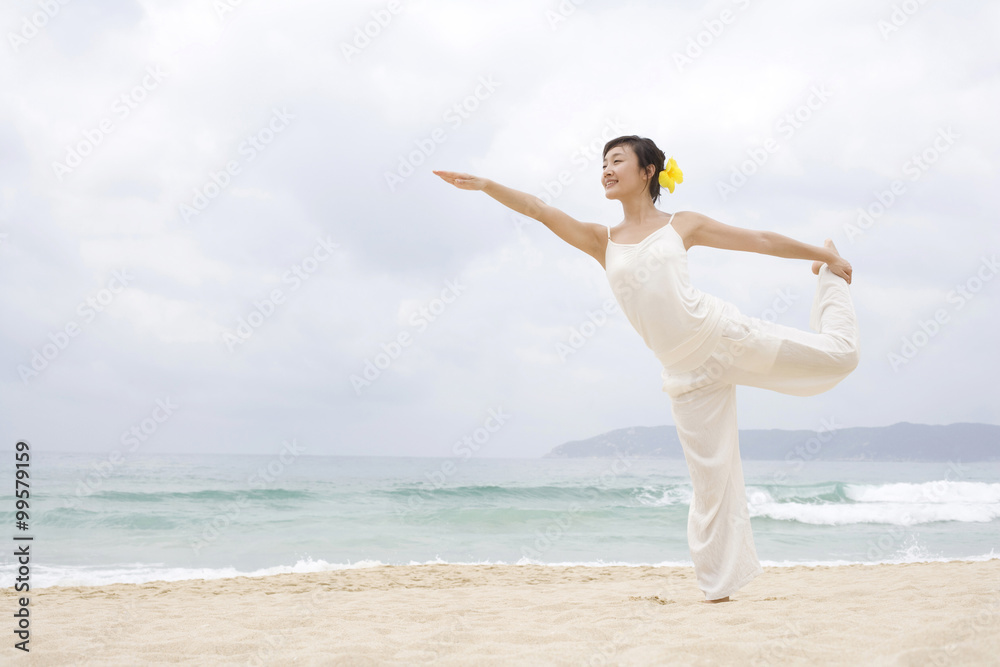 A woman practicing yoga at the beach