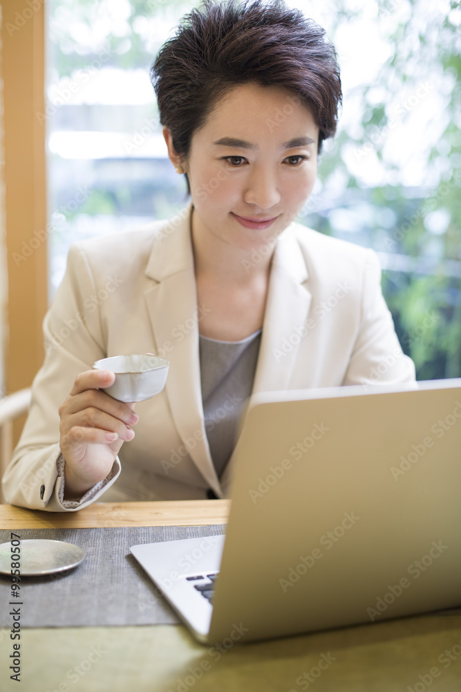 女商人在茶室使用笔记本电脑