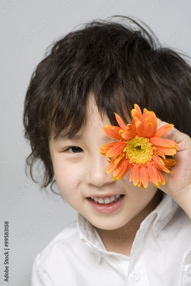 小男孩戴着一朵花遮住眼睛