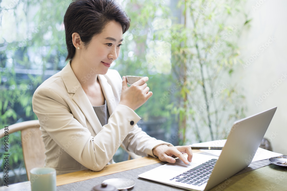 女商人在茶室使用笔记本电脑