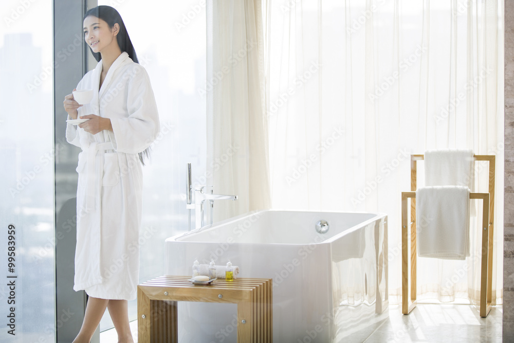 Young woman in bathrobe drinking coffee