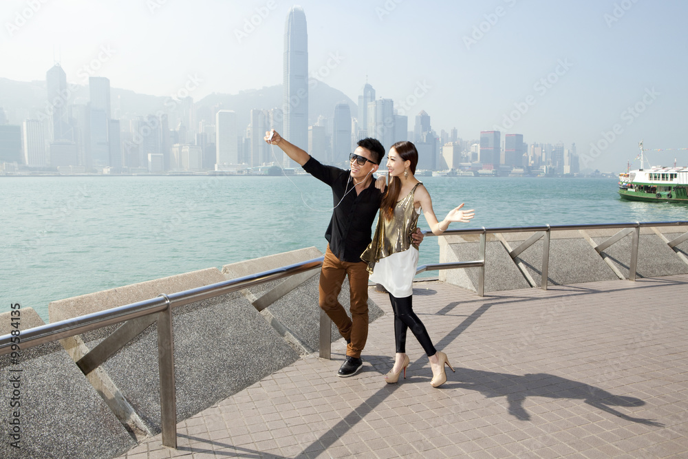 香港维多利亚港时尚年轻情侣用智能手机自拍