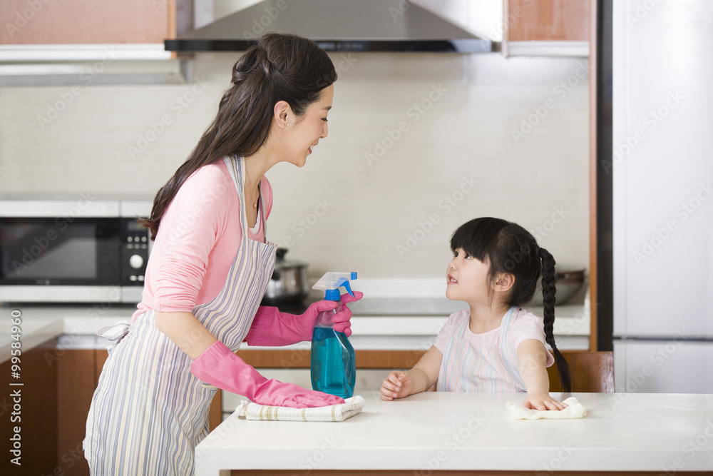 Mother and daughter cleaning kitchen counter