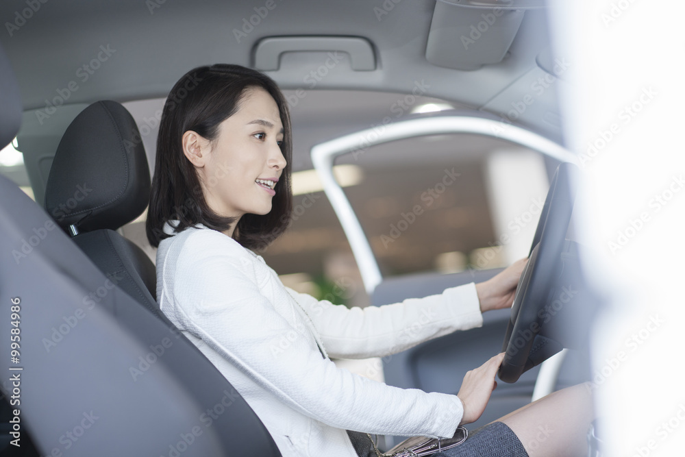 Young woman choosing car in showroom