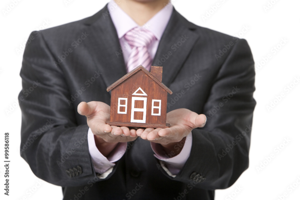 Businessman holding a small wooden model home