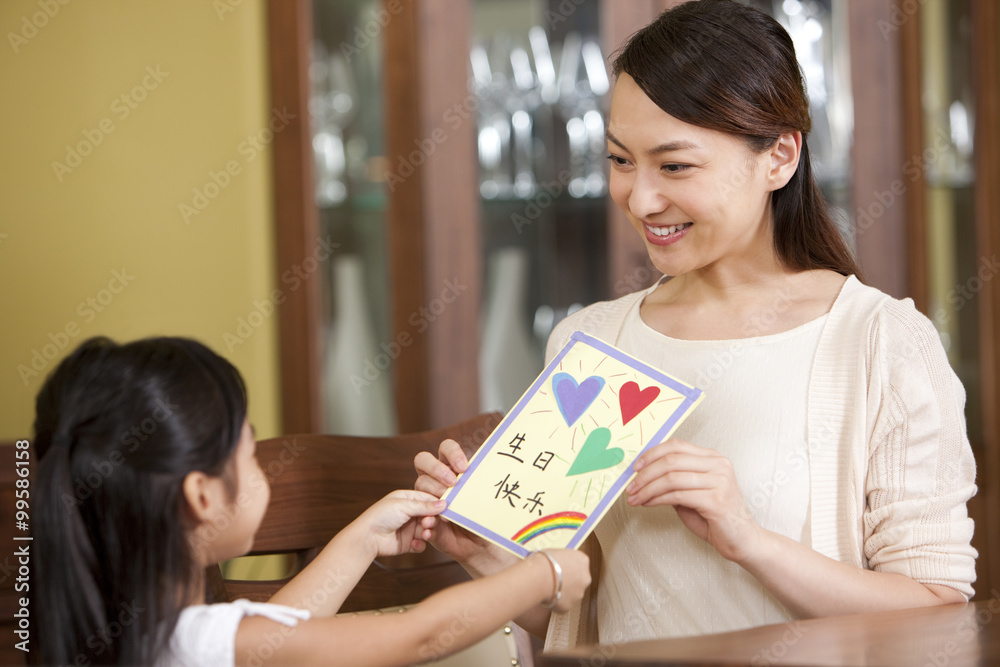 Little girl giving DIY birthday card to mother