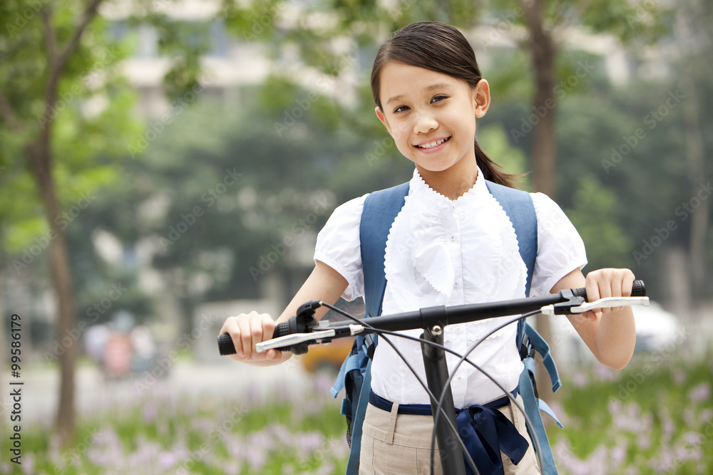 快乐的女学生穿着制服，在户外骑自行车