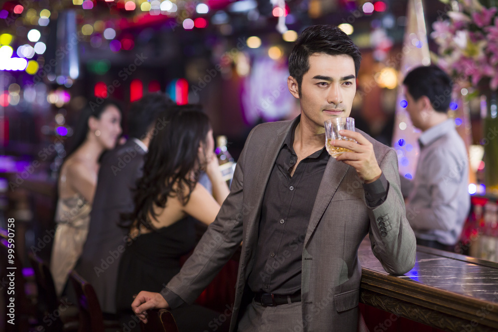 Young man drinking alcohol in bar