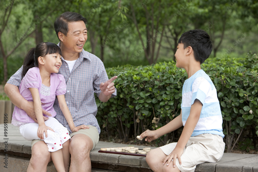 Grandfather playing Chinese chess with grandson and granddaughter