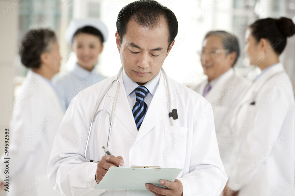 Doctor in Forground with Clipboard, Doctors and a Nurse in Background