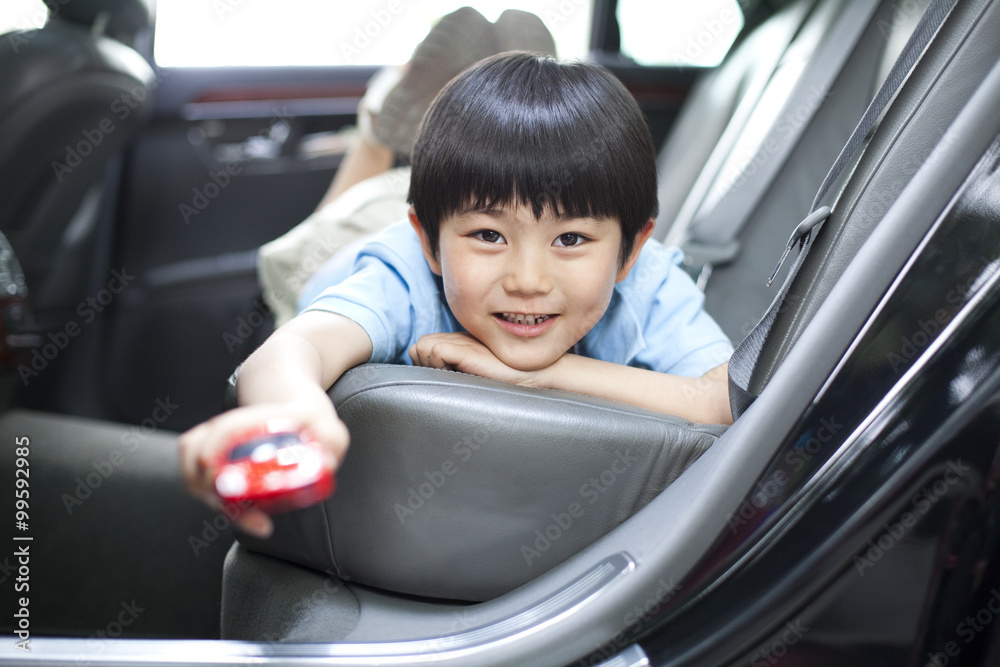 Happy boy lying in car back seat