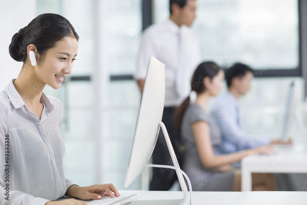 Young businesswoman with Bluetooth headset working in office