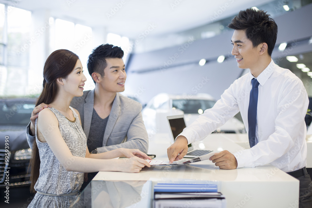 Young couple buying car in showroom