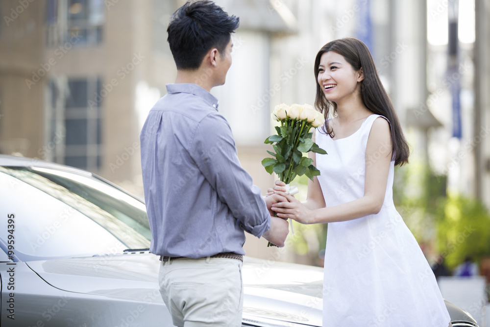 Young man giving flowers to girlfriend