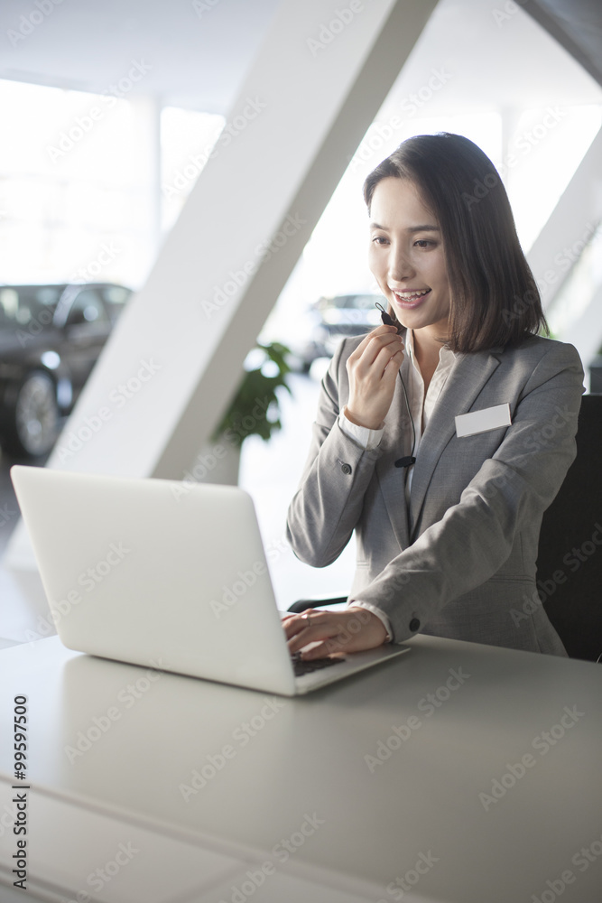 Car saleswoman working with laptop