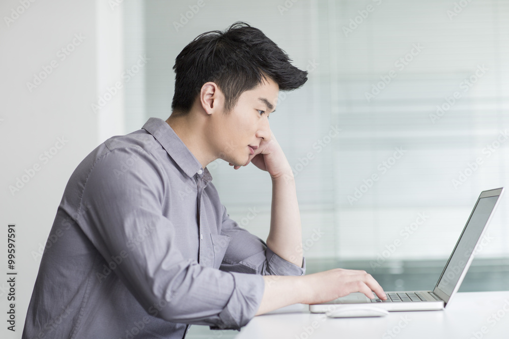 Young businessman using laptop in office