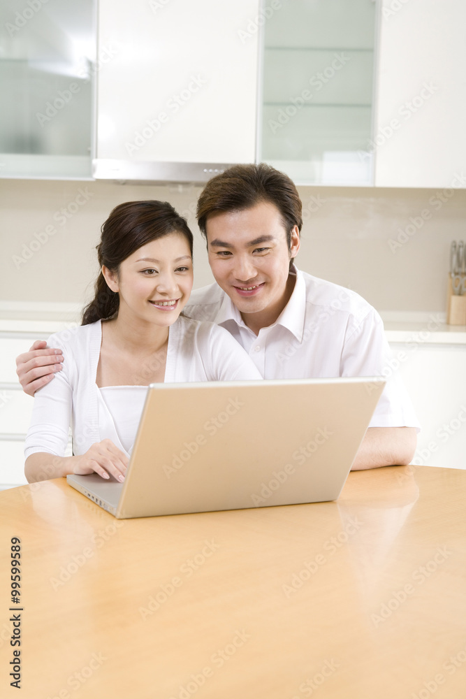 Young couple using a laptop at home