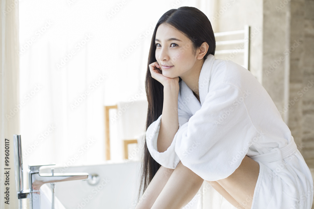 Young woman sitting in bathroom