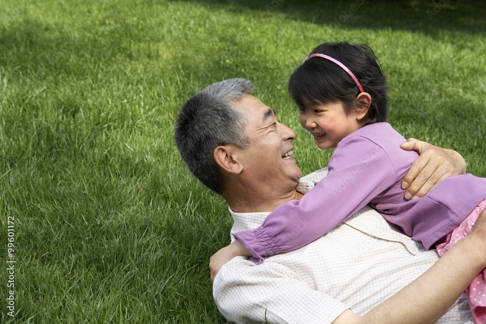 Grandfather And Granddaughter Hugging In The Park